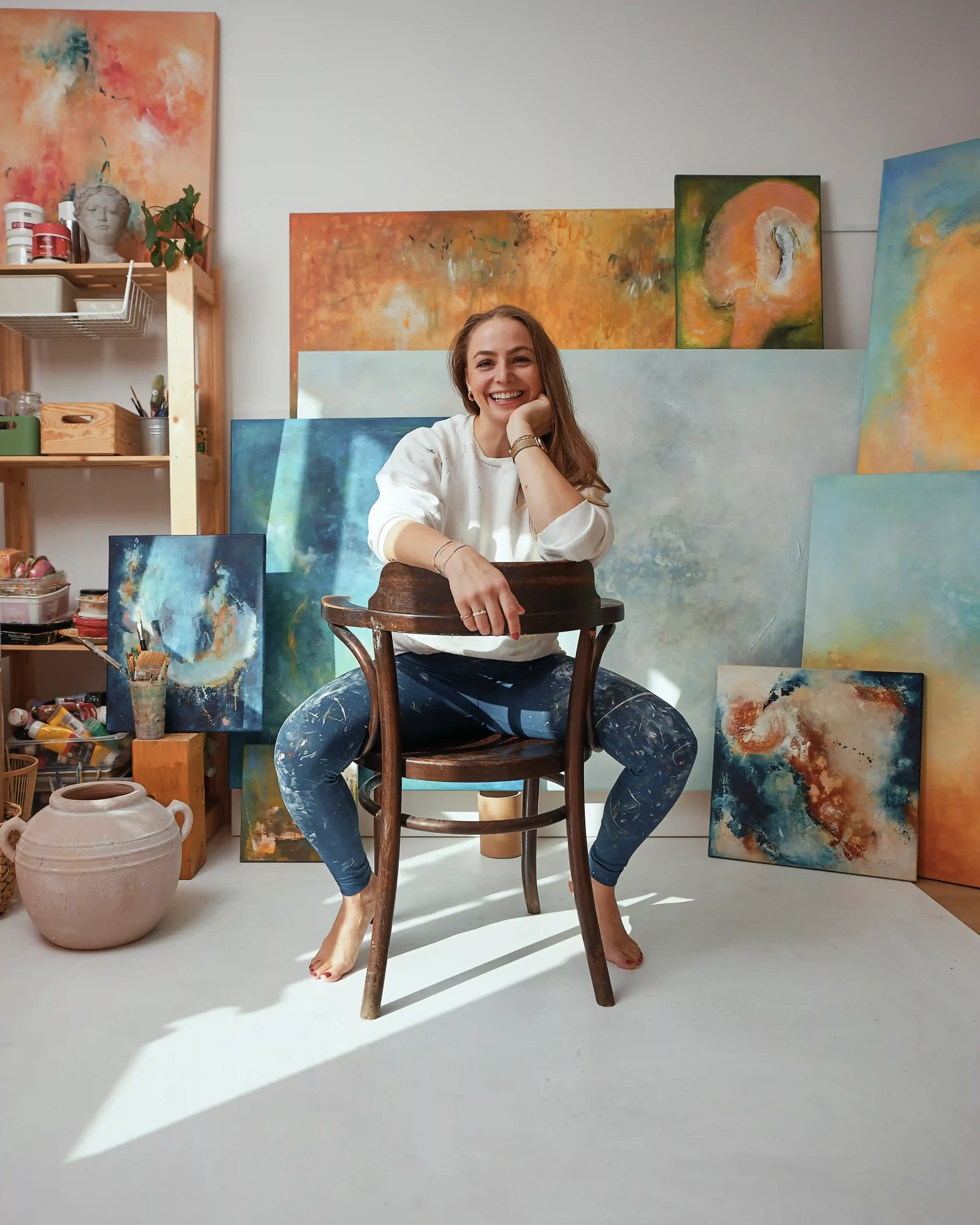 žena na židli s obrazy v ateliéru