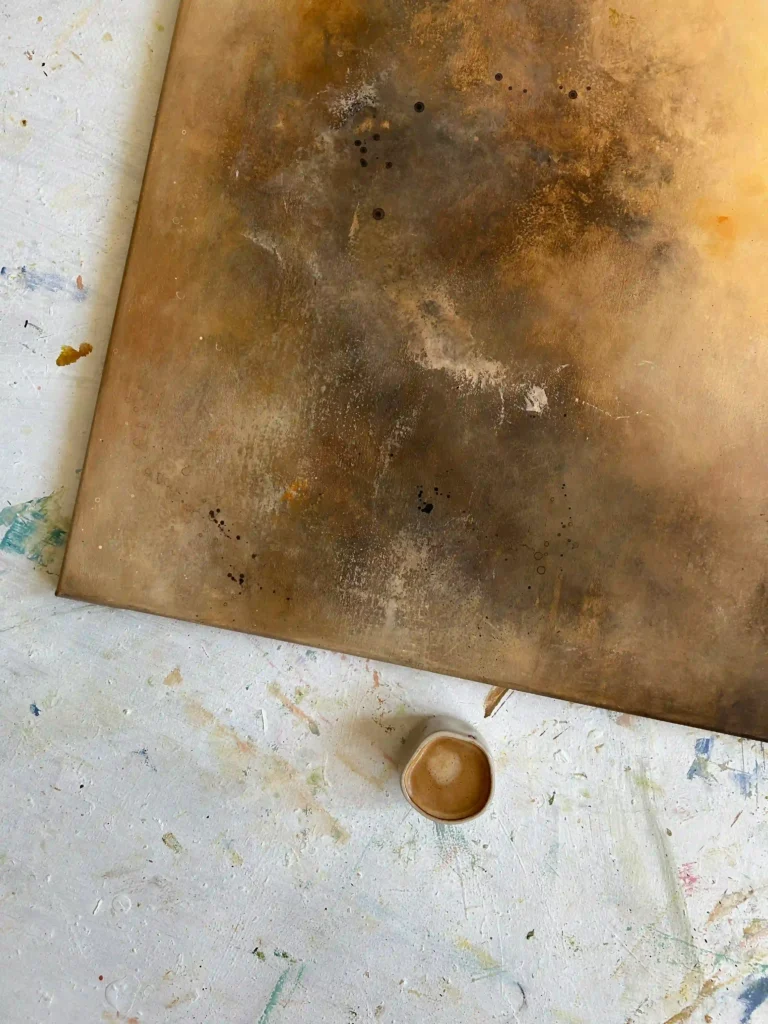 detail oranžovo-hnědý abstraktní obraz v teplých odstínech a káva